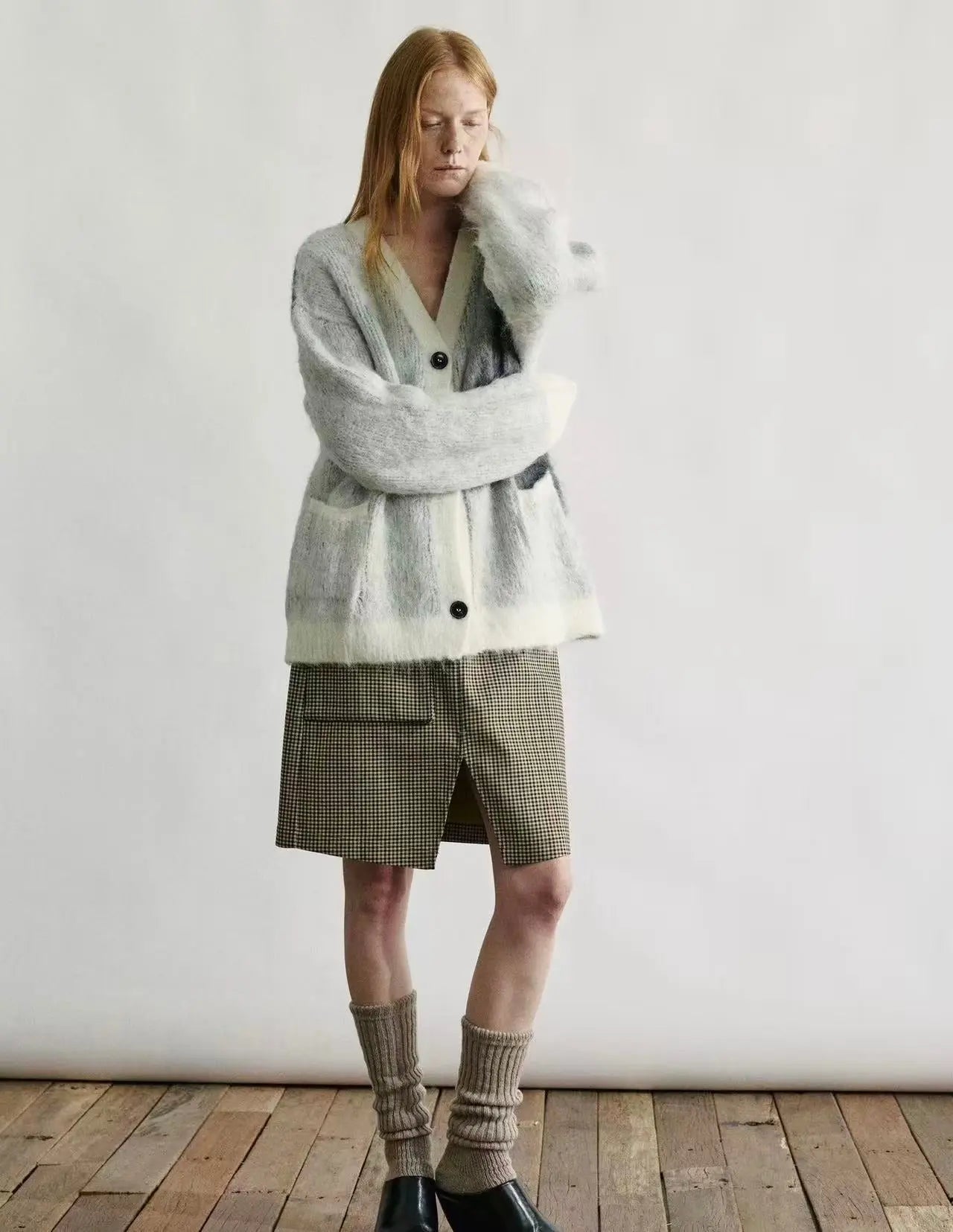 A woman wearing an open-front textured cardigan while relaxing in a cozy, sunlit living room setting