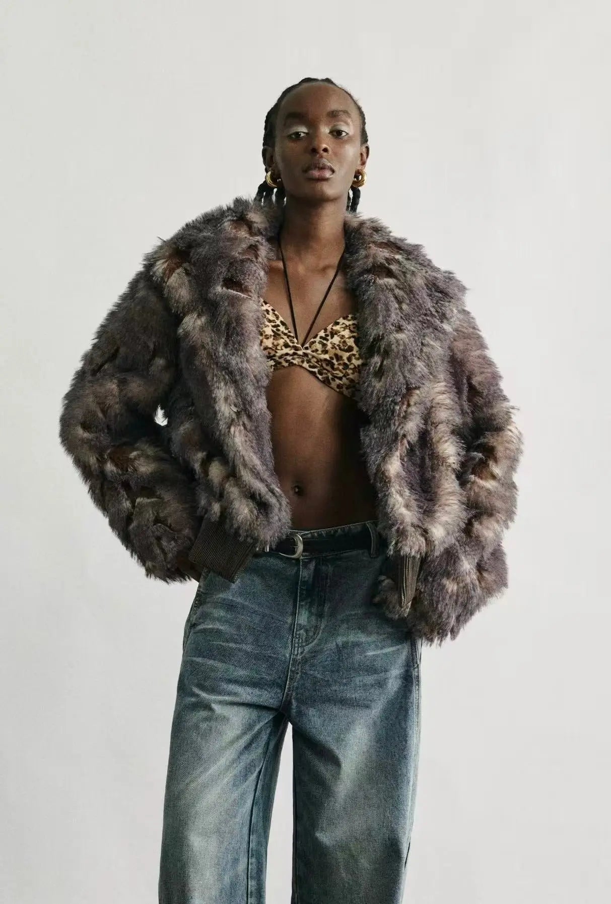 A model wearing the faux fur jacket over an evening dress in a snowy city setting.