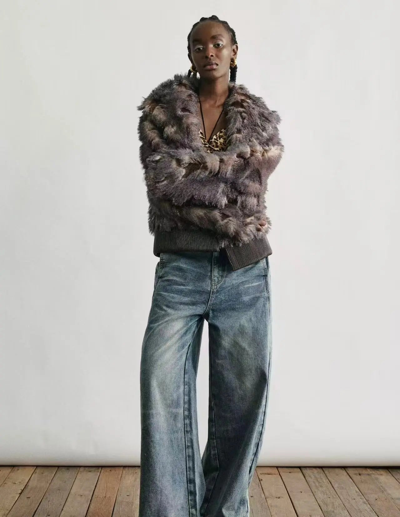A model wearing the faux fur jacket over an evening dress in a snowy city setting.