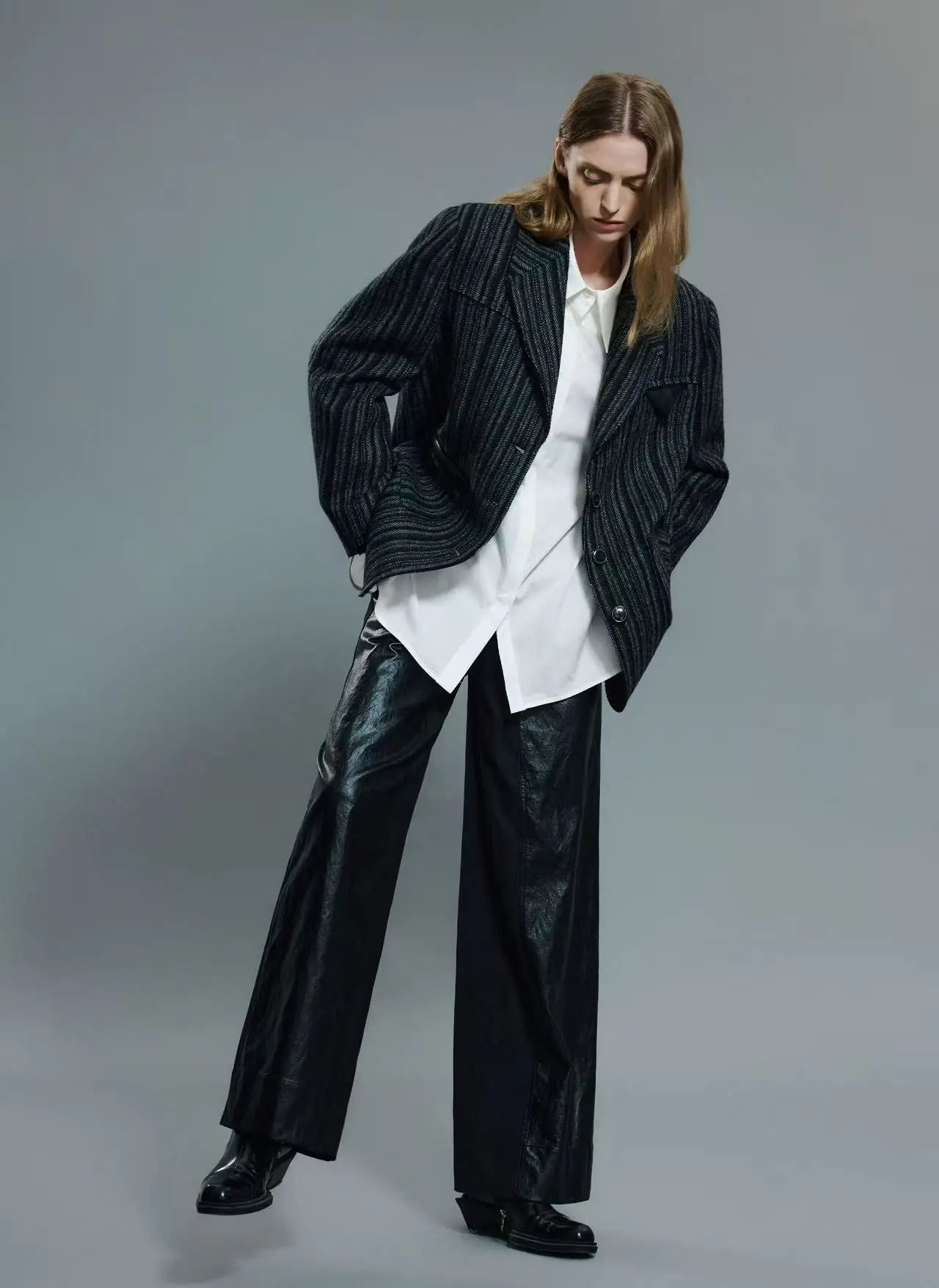 A person styling an oversized jacket with slim-fit trousers and sneakers for a modern urban look.