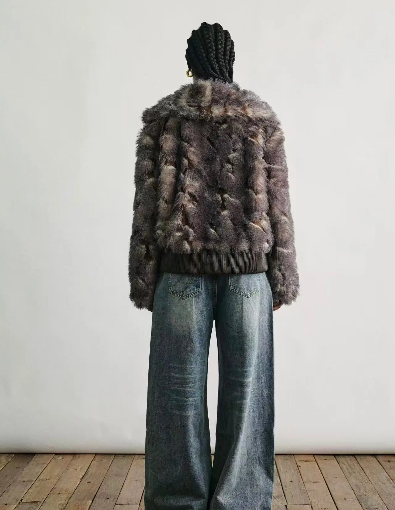 A model wearing the faux fur jacket over an evening dress in a snowy city setting.